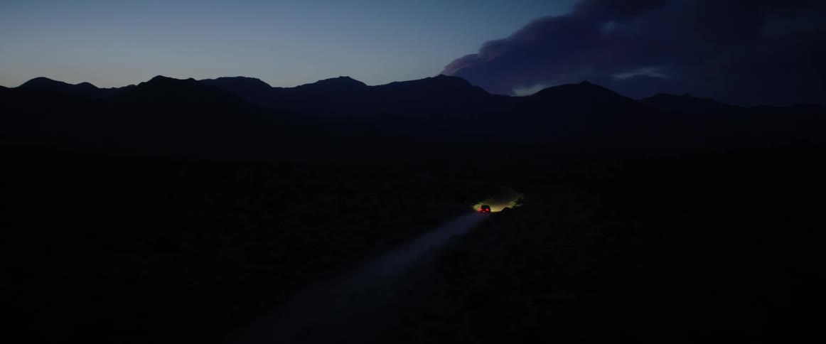 Aerial of a vehicle moving on a sandy road at night