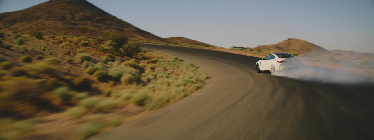 White bmw coup performing drifts on curved streets in the middle of the desert
