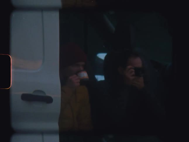 Friends drinking and taking photos sitting in a van parked on the street