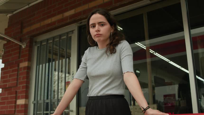 A teenage girl standing in front of a building