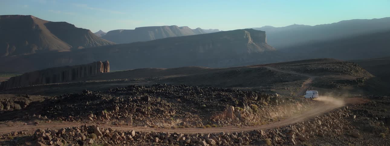 A van driving through a dirt road in the valley