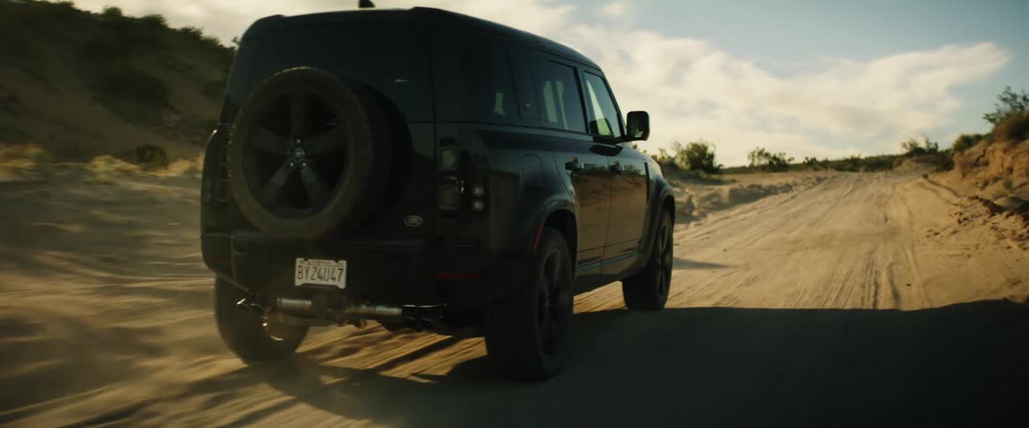 A sports car driving along a dirt road in the desert on a hot day