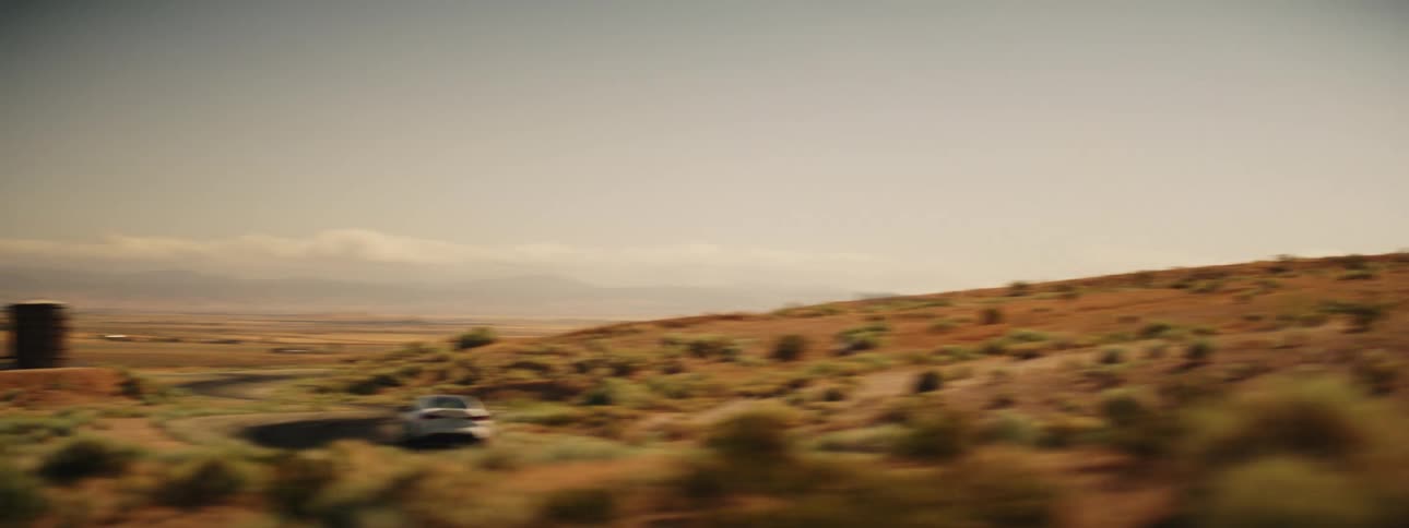 White sports bmw speeding along a road in a desert location