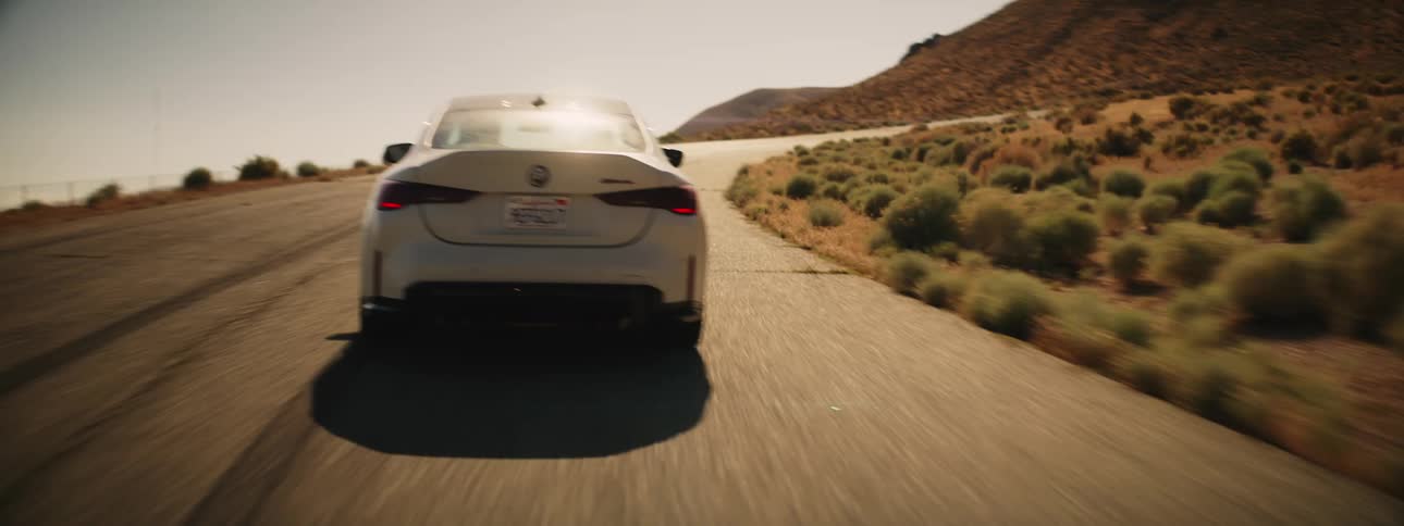 A white car driving on a road on the desert hills