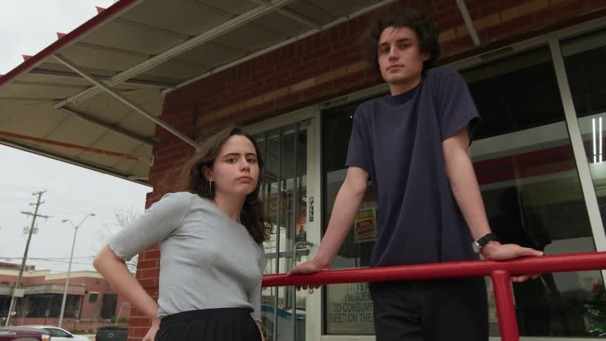 Two young teenagers on a handrail of an outdoor establishment