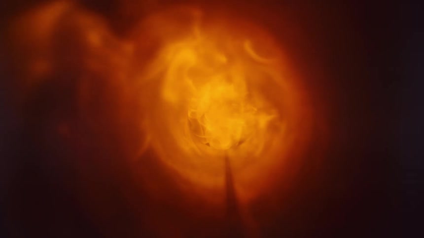 Fire bursts in and flames swirl down and out against the black