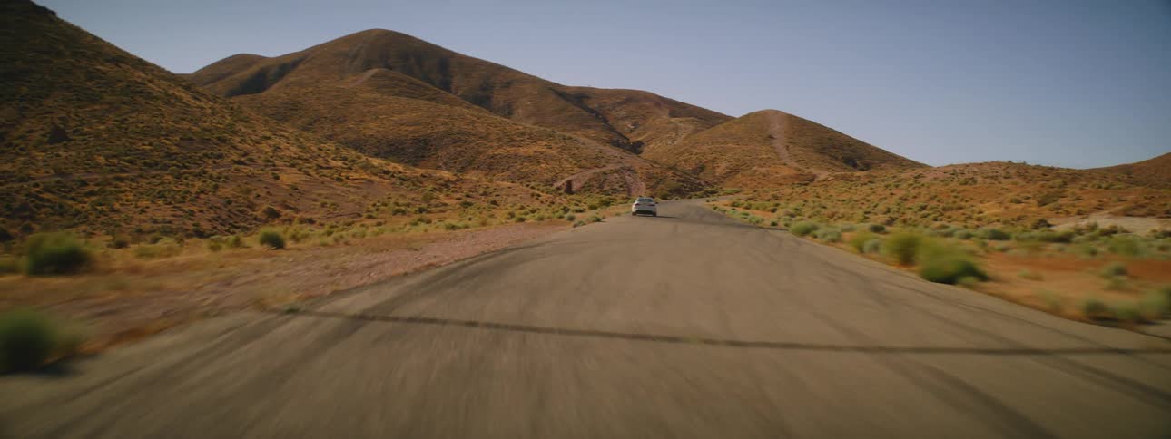 A car speeds down a road in a desert