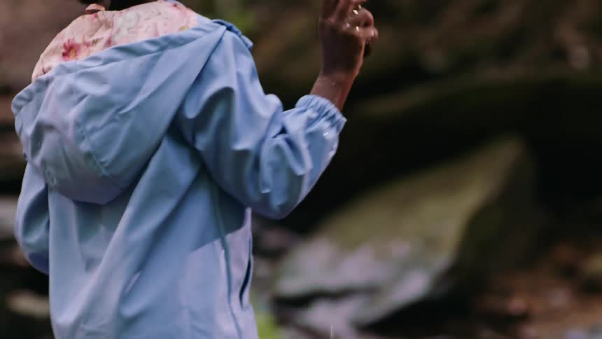 A girl picks up a stone from a lake in the forest