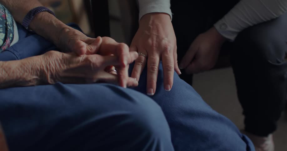 A female care worker comforts her patient patting her leg