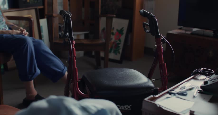 A woman sits in the room near her walker