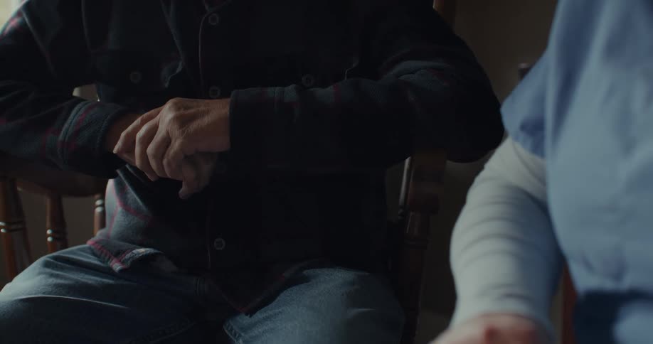 Two people with their faces not visible hold hands in a gesture of comfort