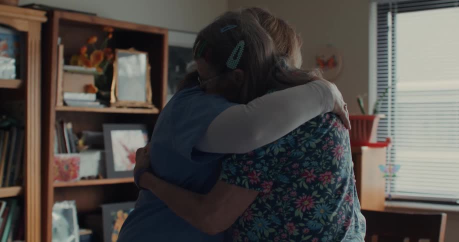 A female care worker gives her patient a hug patting her back