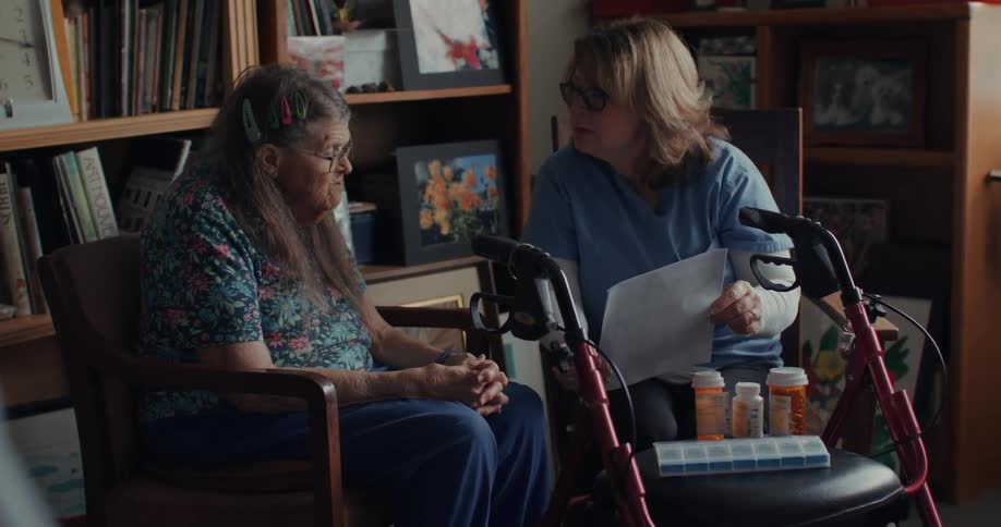 A nurse is reading paperwork to an elderly woman