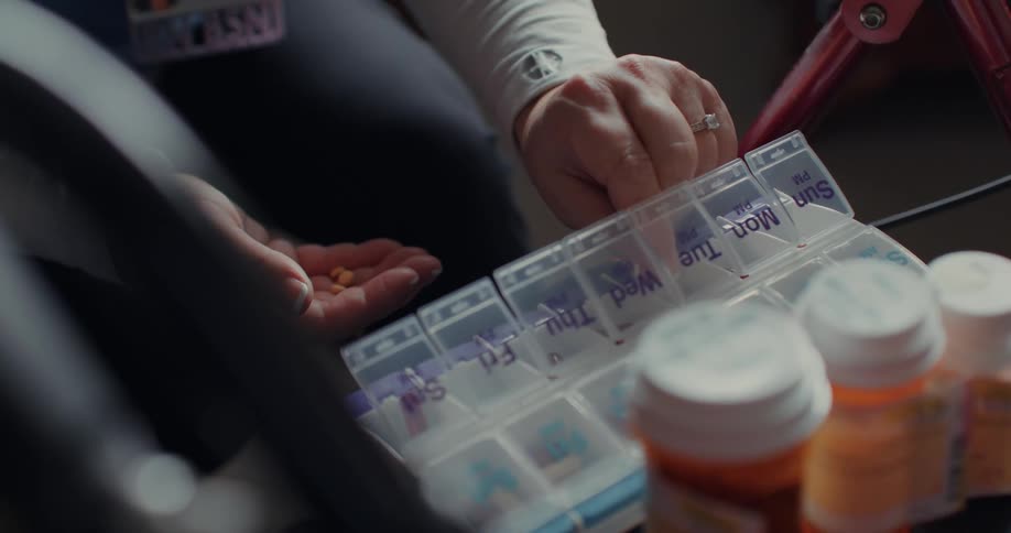 Woman sorts her prescription medications into a weekly pill organizer