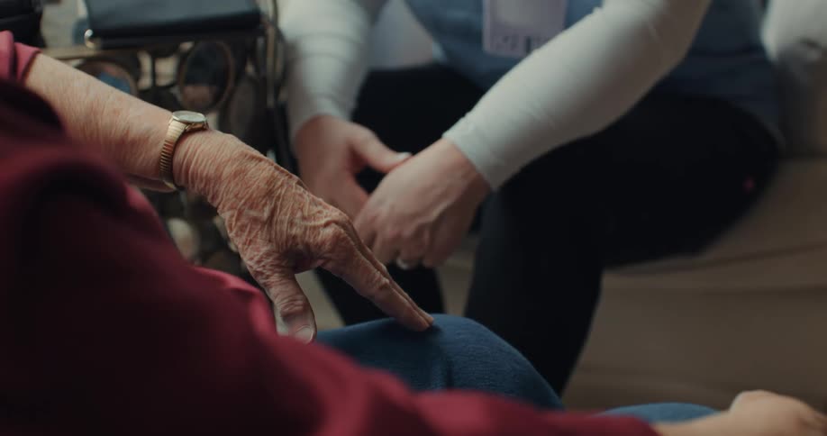 A nurse sits with an elderly patient