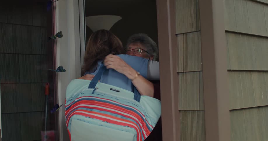 Elderly mother greets her daughter at the doorway of her house
