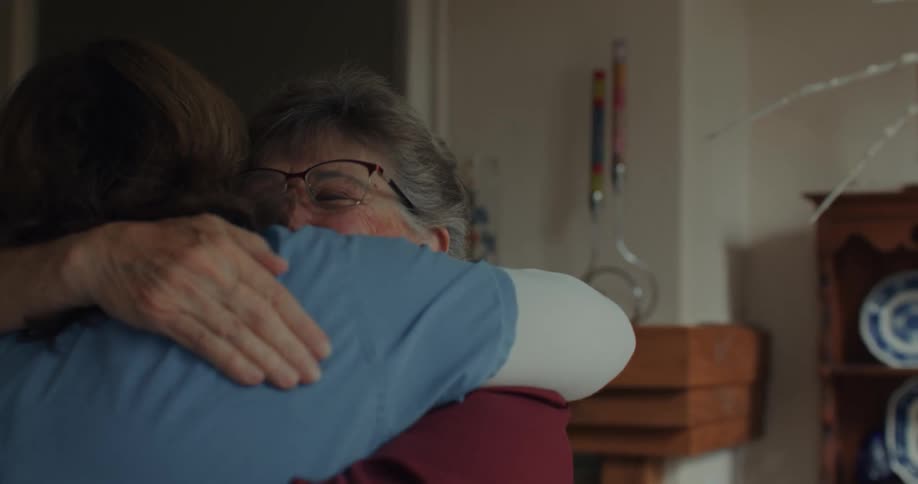A nurse and patient hug at home