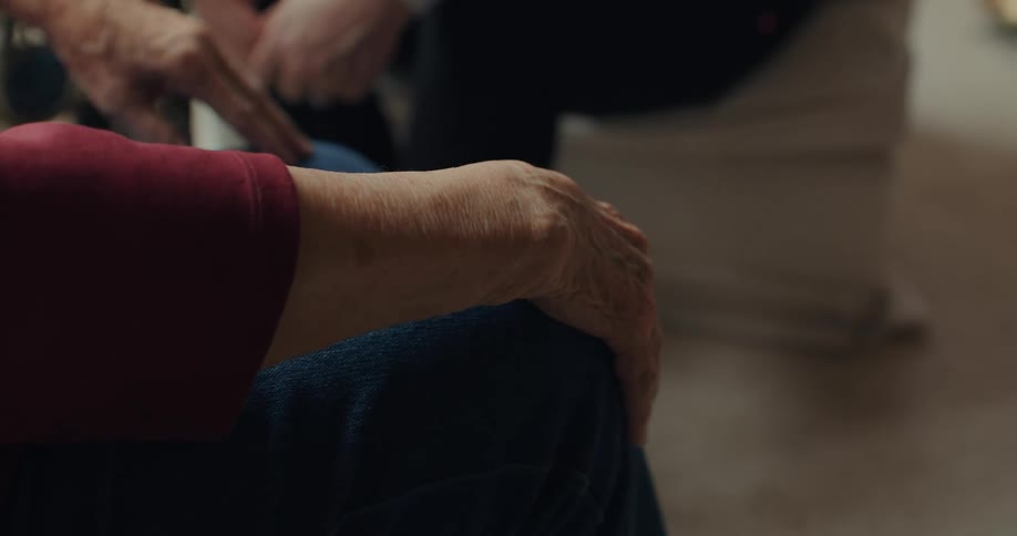 A person sits rubbing their hands anxiously over their jeans