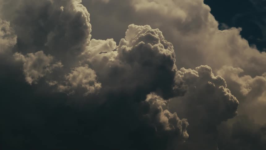 Dark clouds gather illuminated by sunlight in the sky