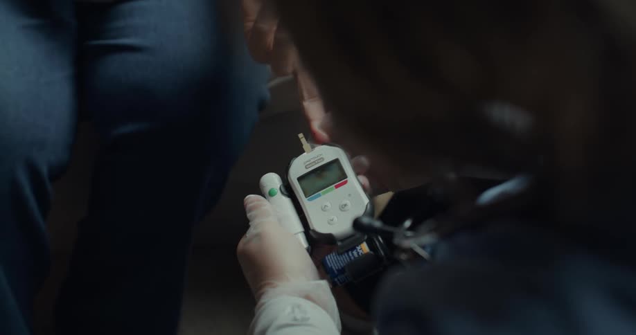 Nurse uses glucometer on middle finger of her patient