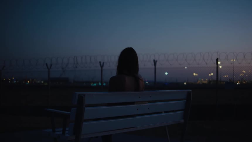 A woman sits on a bench outdoors