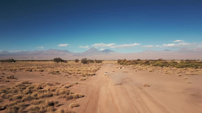 A vehicle gives off a dust cloud as it drives through the desert