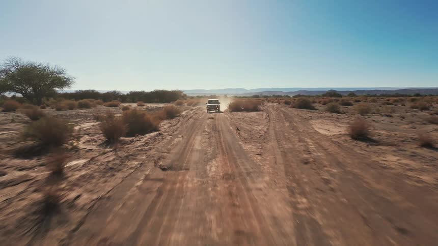 A vehicle races through a desert