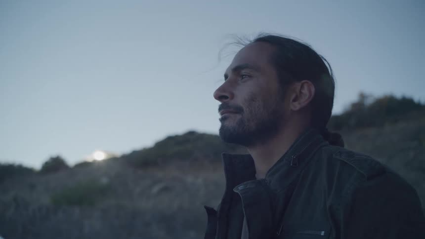Man takes in his surroundings on a mountain at dawn
