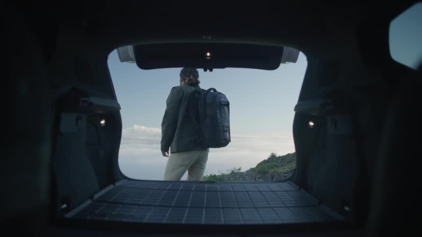 A hiker takes his backpack from the truck