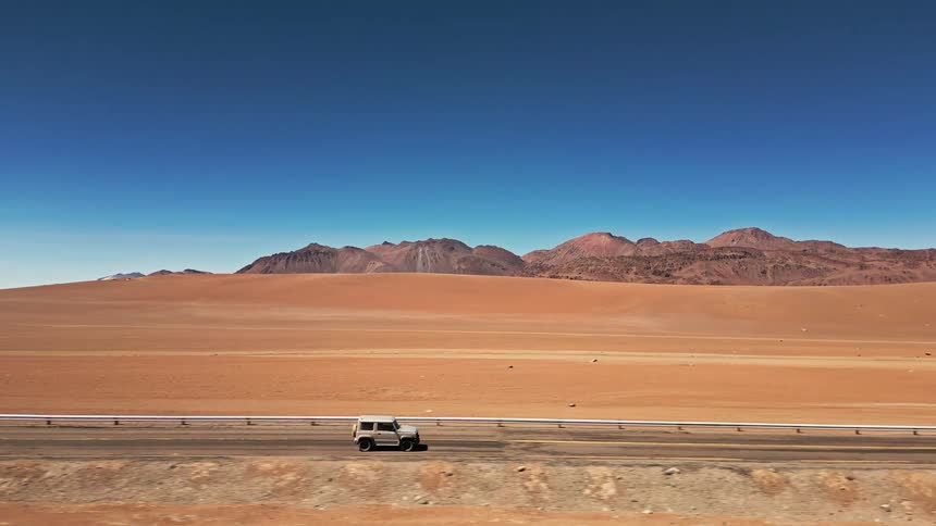 A vehicle drives down a desert road