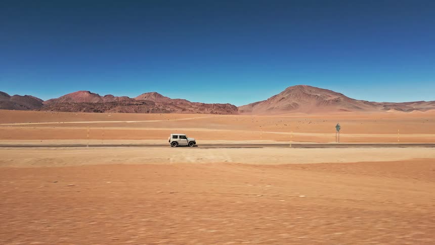 A vehicle drives on a desert road
