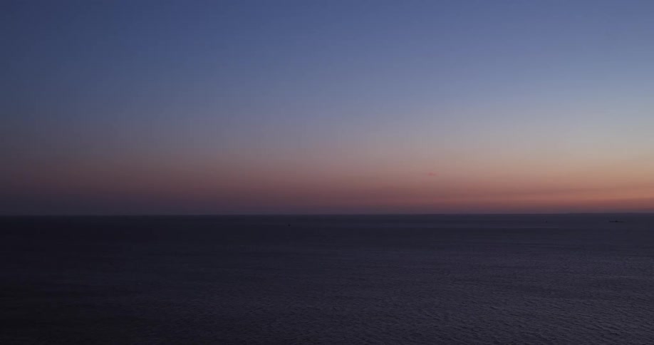 The horizon lights up from sunlight over an ocean