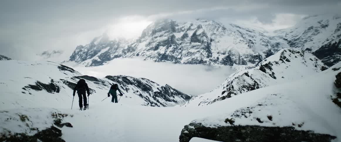 Two people with appropriate equipment performing snowcovered mountain porn skiing on a diamond