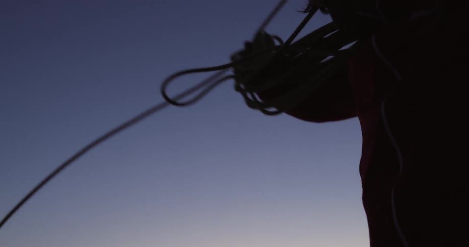 A person is pulling a rope and wrapping it around his arm on a clear morning