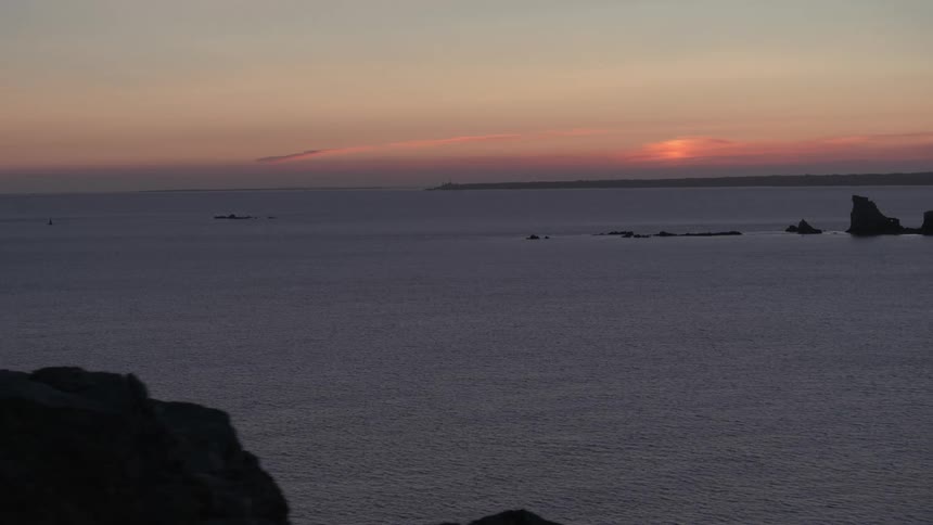 Gentle waves in the ocean beyond the cliff at sunset