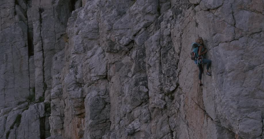 A person is rock climbing on a steep rugged cliff