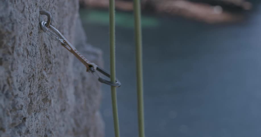 A metal hook is hanging onto a small rope in the rain
