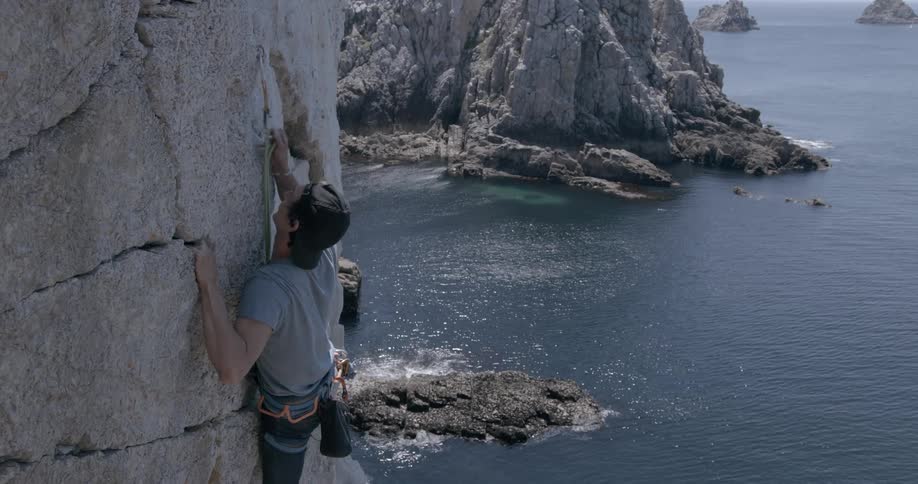 A man climbing a rock near the ocean shore