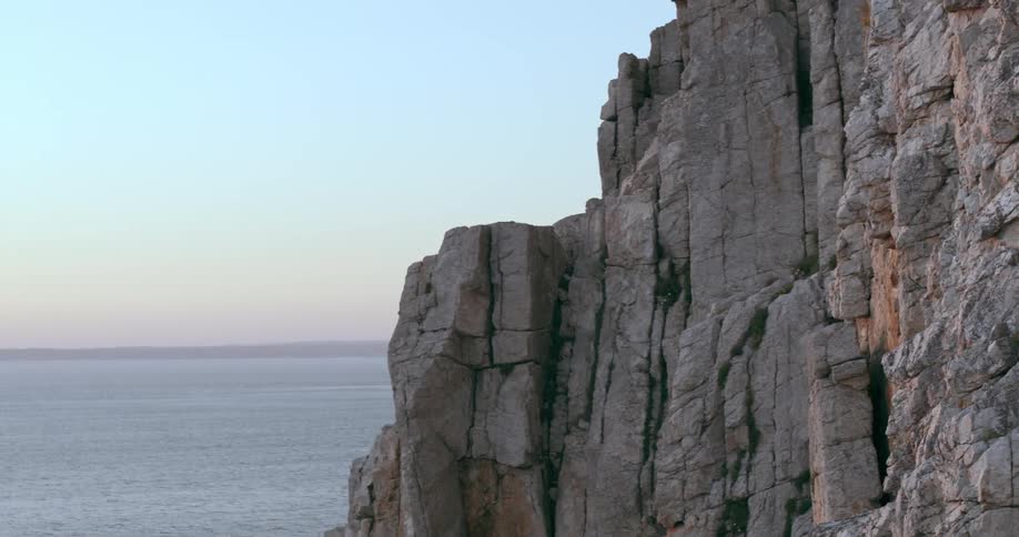 Two climbers ascend a rugged cliff face next to the ocean