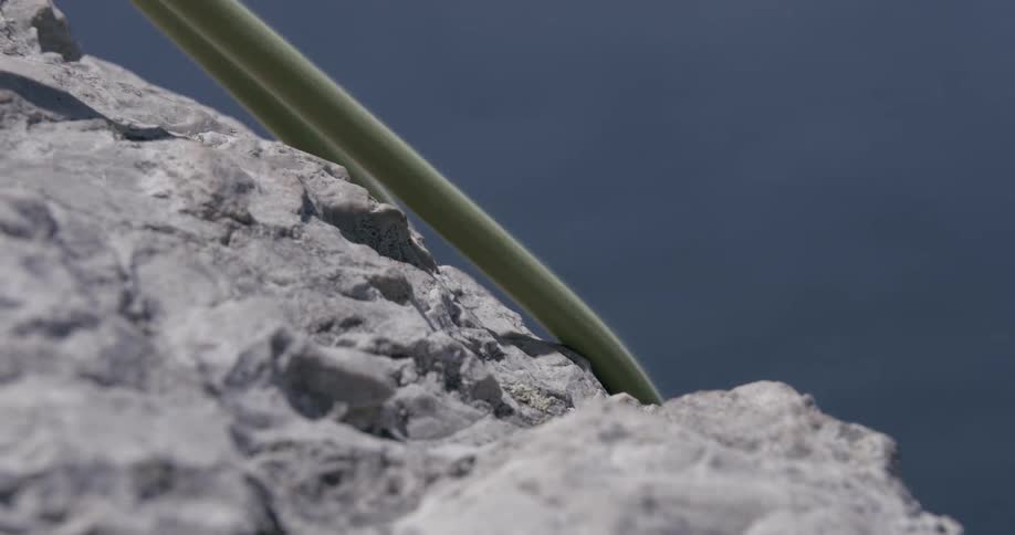 A yellow rope brushing the edge of a roughsurfaced stone
