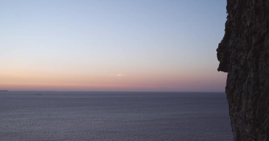 Natural landscape of the rocky coast next to the sea on a red sky morning
