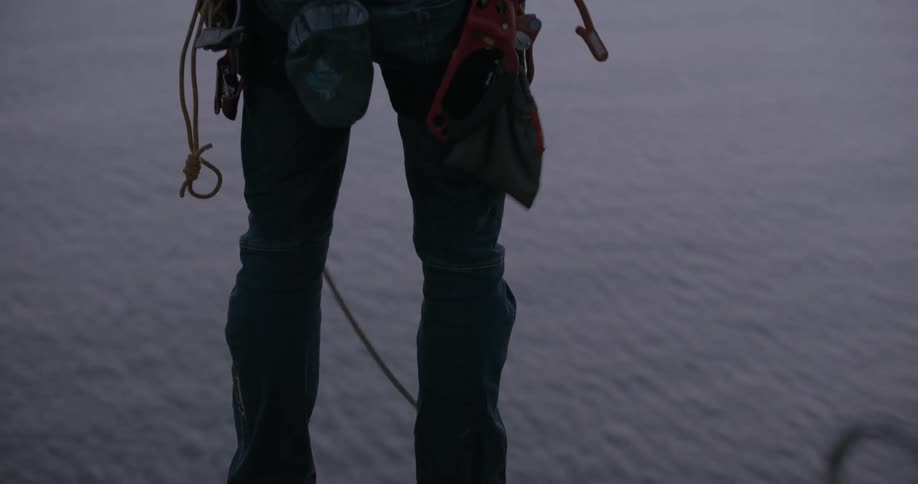A person setting up ropes on top of a mountain close to the ocean