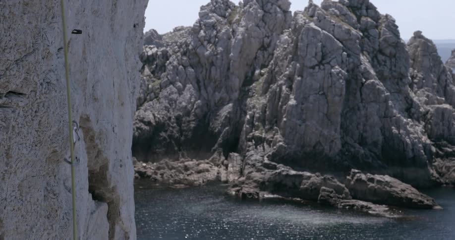 Rope hanging from the side of a cliff next to the ocean