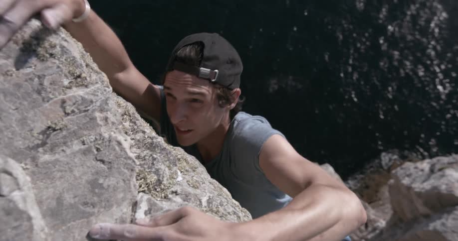 A man practices climbing with the sea in the background