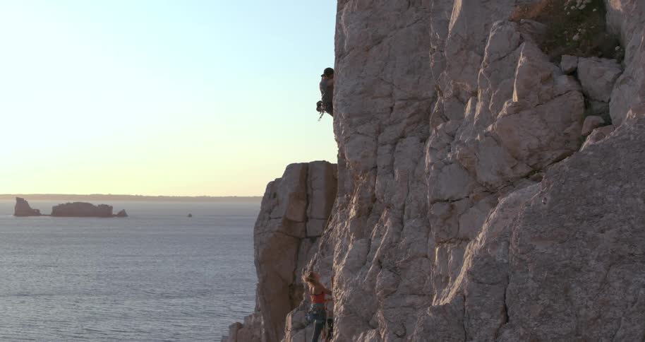 A person mountain climbing with the mountain close to the ocean