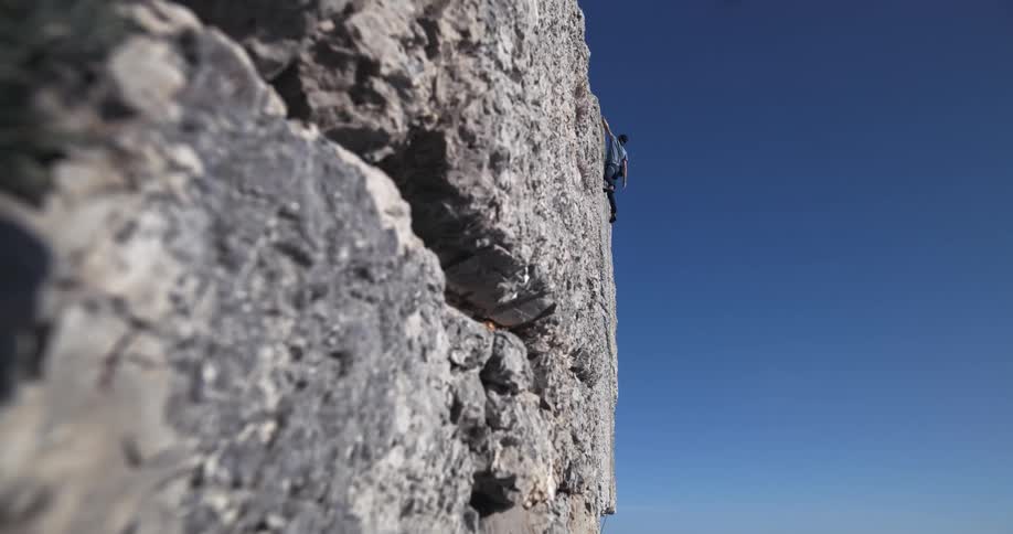 A rock climbing is hanging from the cliff