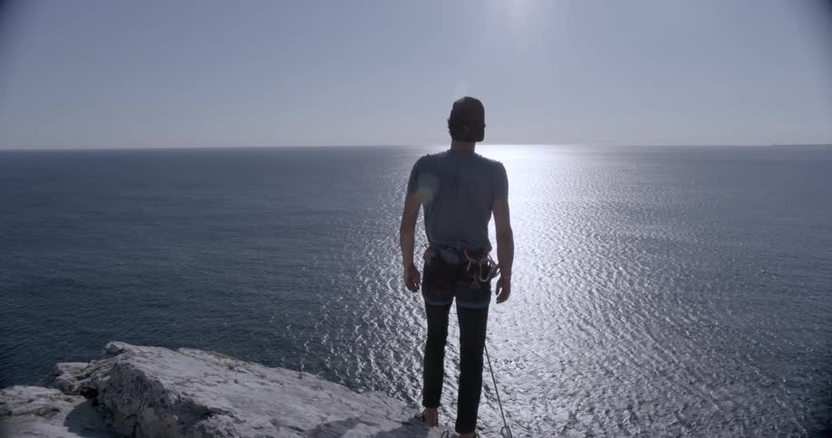 A rock climbing stands close to the edge of the cliff