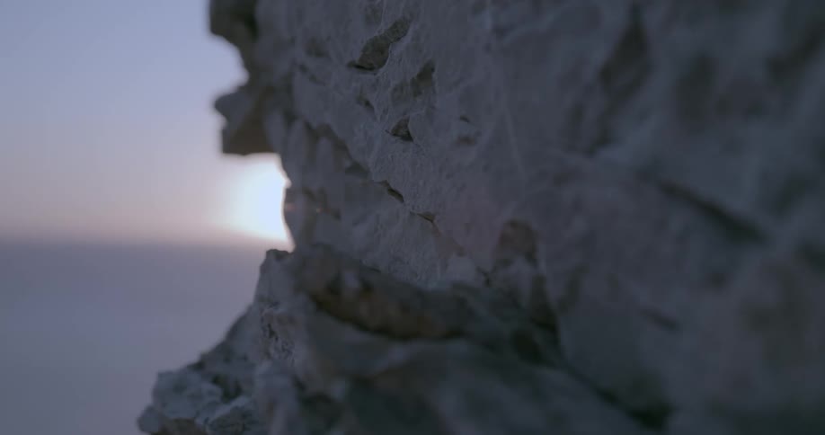 Porous rock mountain in front of an ocean at sunrise