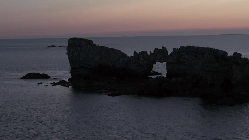 Landscape of mountainous rocks in the middle of the sea in a reddish sky