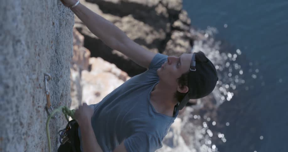 A man climbing a rock close to the ocean